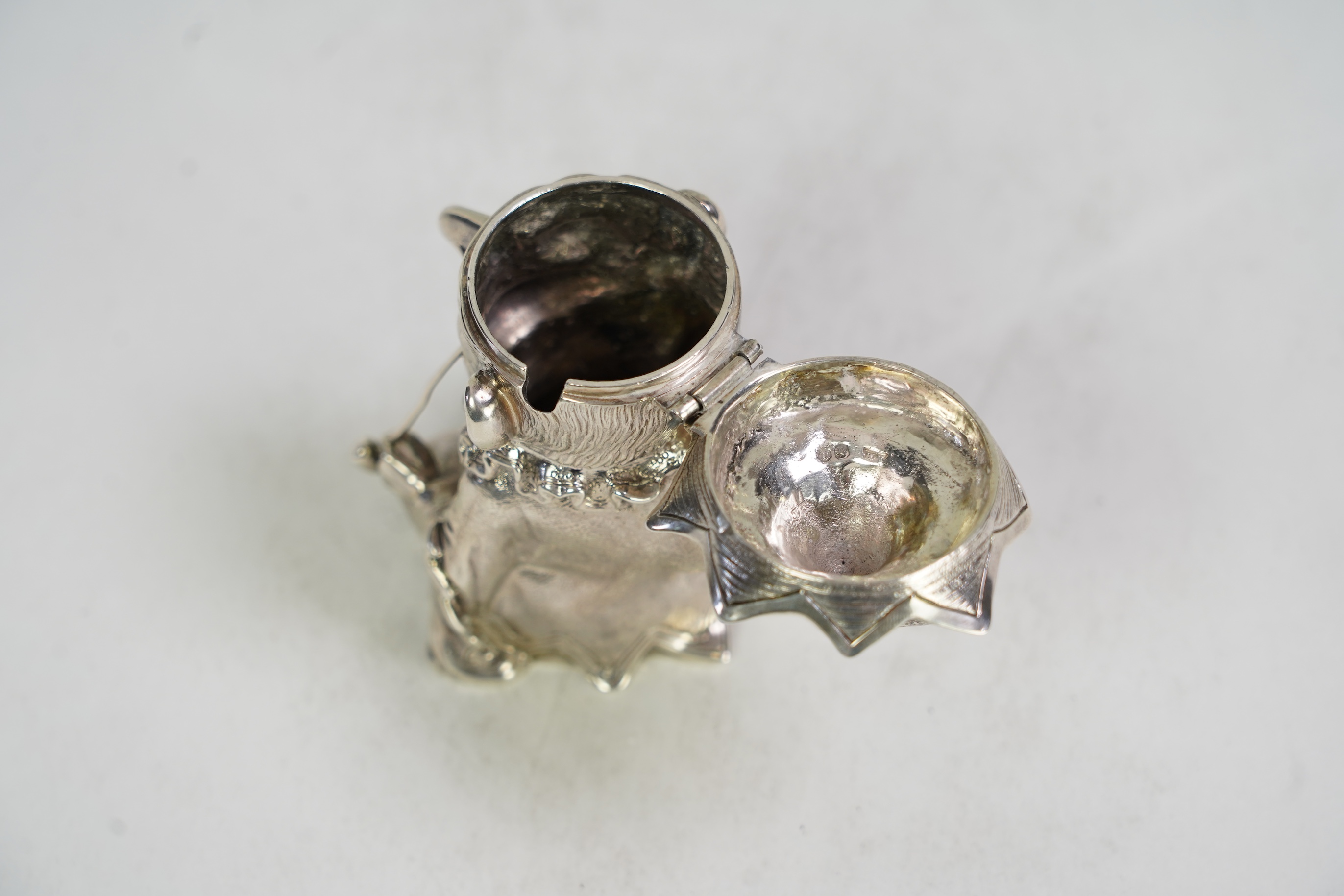 A rare Victorian novelty cast silver mustard pot, modelled as seated cross-legged Mr. Punch, holding a wine glass and smoking a pipe, by Robert Hennell III